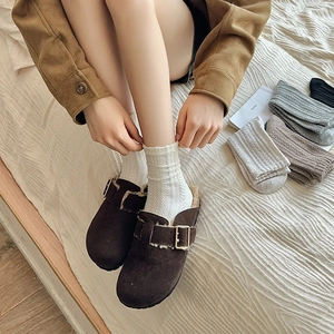 Détail de mules en daim marron foncé avec doublure et chaussettes blanches en maille