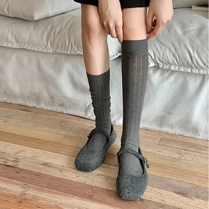 Detailed texture of grey vertical striped knit socks worn with Mary Jane shoes