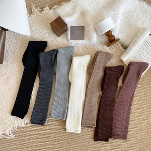 Detailed knit texture of multi-color ribbed leg warmers in cozy home setting