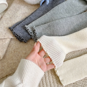 Detail of ribbed knit leg warmers with delicate ruffle edges and elastic wool texture