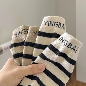 Close-up of wool-blend striped socks with letter embroidery and ribbed knit texture