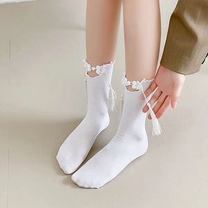 Detail of white rib-knit sock with traditional Chinese frog button and silk tassel trim