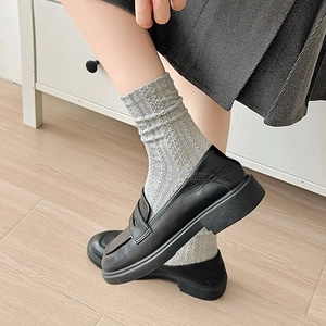 Détail de chaussettes en maille à rayures verticales grises avec mocassins noirs à plateforme