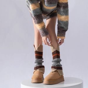 Close-up of striped knit leg warmers paired with platform suede winter snow boots