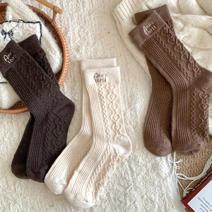 Detailed knit texture of wool socks featuring heart patterns and letter embroidery