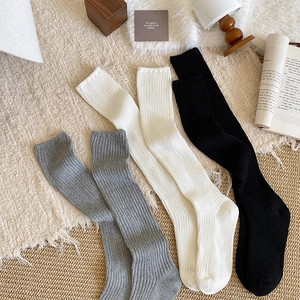Detailed close-up of ribbed knit texture on gray, white, and black cotton mid-calf socks
