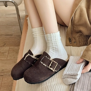 Détail de mules en daim marron foncé avec doublure polaire et boucle en métal