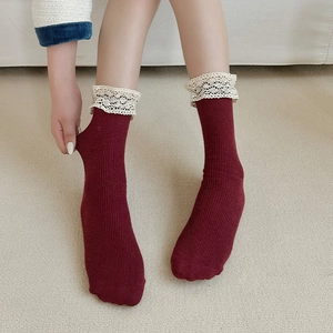 Detail of burgundy ribbed socks with white lace trim showing high elasticity and soft texture