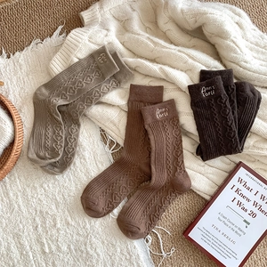 Detailed knit texture of wool mid-calf socks with heart pattern and letter embroidery