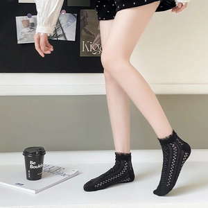 Détail de chaussettes en dentelle noire avec motif damier et bordure à volants