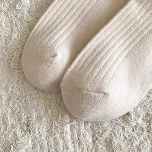 Macro detail of beige ribbed knit wool socks showing high-quality texture and stitching