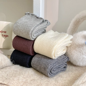 Detailed close-up of ribbed wool leg warmers in five colors with scalloped edge detail