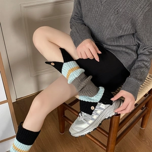 Close-up of striped knit leg warmers featuring contrast colors and wooden button details