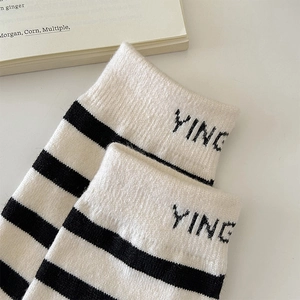 Detail of striped wool socks with YING letter embroidery and knit texture on white desk