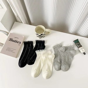 Détail de la bordure en dentelle sur trois paires de chaussettes en maille ajourée douce