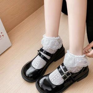 Detail of black patent leather Mary Jane shoes with double straps and lace socks