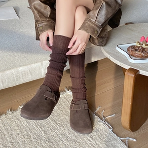 Close-up of brown textured calf socks paired with vintage-style suede buckle mules