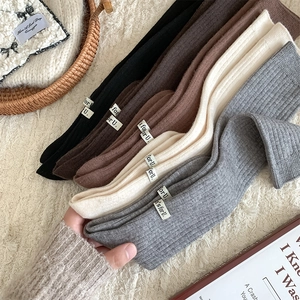 Close-up of thick ribbed wool knee-high socks in multiple colors with fashion labels