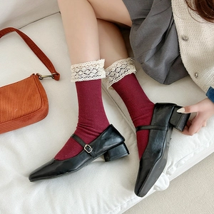 Close-up of vintage lace trim on dark red knit socks paired with black Mary Jane shoes