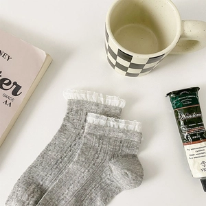 Détail de chaussettes en tricot gris avec bordure en dentelle blanche et texture côtelée