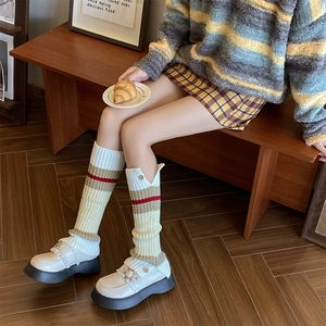 Detail of knit leg warmers with button accents and contrast stripes paired with loafers