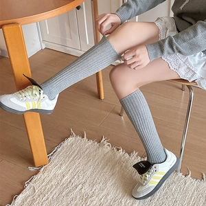 Detail of grey ribbed knee-high socks showing the fine knitted texture and snug fit