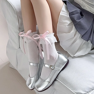 Nahaufnahme weißer Spitzensocken mit rosa Seifenschleifen und silbernen Mary Janes