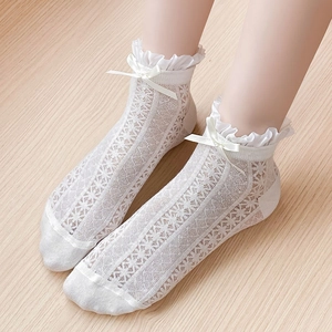 Close-up of white lace mesh socks with ruffled trim and satin bow detail for girls
