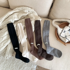 Flat lay of ribbed wool-blend knee-high socks in five neutral colors with woven labels