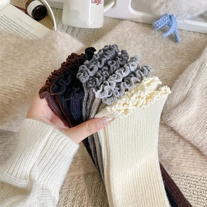 Close-up of ribbed wool leg warmers with ruffle cuffs in various neutral colors