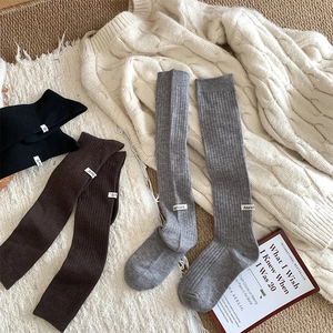 Close-up of ribbed wool knee socks in black and brown with Ann's for U label detail