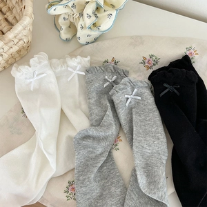 Detail of ruffled cuffs and bows on knit socks in white, black and gray colors