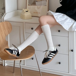 Detail of white ribbed knee-high socks with vertical stripes in a retro academic style