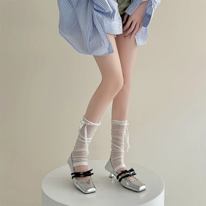Close-up of silver Mary Jane pumps with black bows and white lace mesh socks