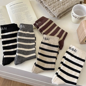 Assorted colorful striped wool mid-calf socks with letter embroidery on white table