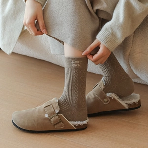 Detail of wool socks with heart knit patterns and suede slippers with faux fur lining
