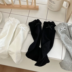 Detailed view of ruffle lace trim and ribbon bows on white, black, and grey socks