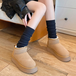 Camel suede snow boots with plush lining and black leg warmers in a cozy home setting