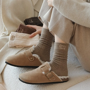 Detail of wool socks with heart patterns and letter embroidery paired with mule shoes