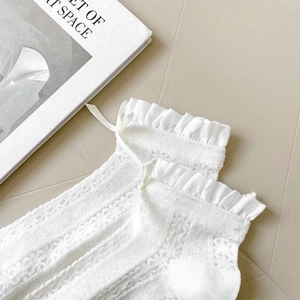 Detail of white lace hollow socks with ruffled edges and silk ribbon bow decoration