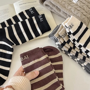 Detail of warm striped wool crew socks with letter embroidery and thick knit texture