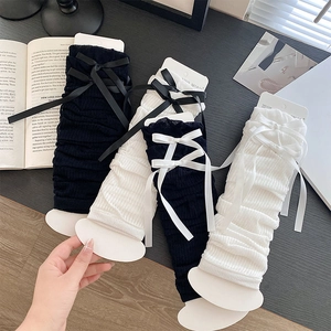 Detail of ribbed knit leg warmers with satin bows displayed on packaging cards