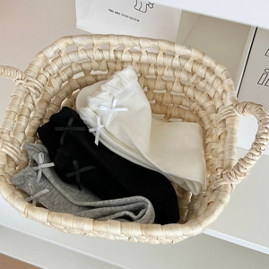 Detailed view of three pairs of cotton socks in white, black and gray with bow details