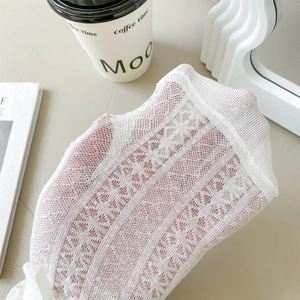 Detailed macro view of white lace mesh socks showing delicate floral knit texture