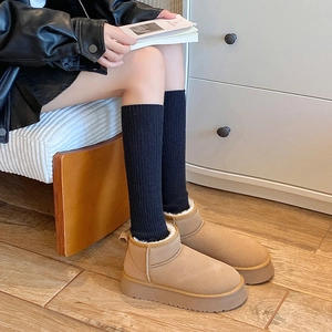 Close-up of camel suede platform snow boots with warm faux wool lining and black ribbed socks