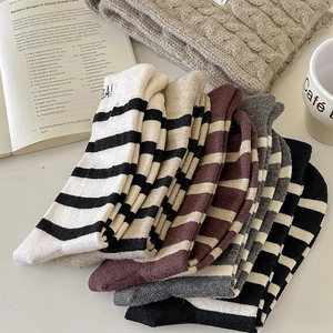 Close-up of striped wool knit socks in various colors stacked on a minimalist background
