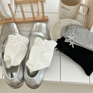 Close-up of frilly lace socks with delicate bows in white, grey, and black cotton fabric