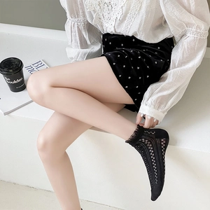 Détail des chaussettes en dentelle noire avec bordures festonnées et texture à pois