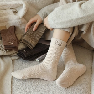 Thick wool socks with letter embroidery and cable knit pattern in earthy tones
