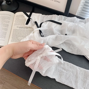 Close-up of white ribbed arm warmers with delicate ribbon bows in Balletcore style